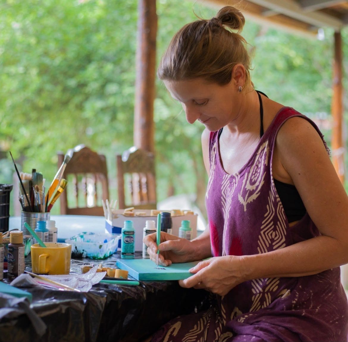 Artista pintando a mano una pieza turquesa en el taller